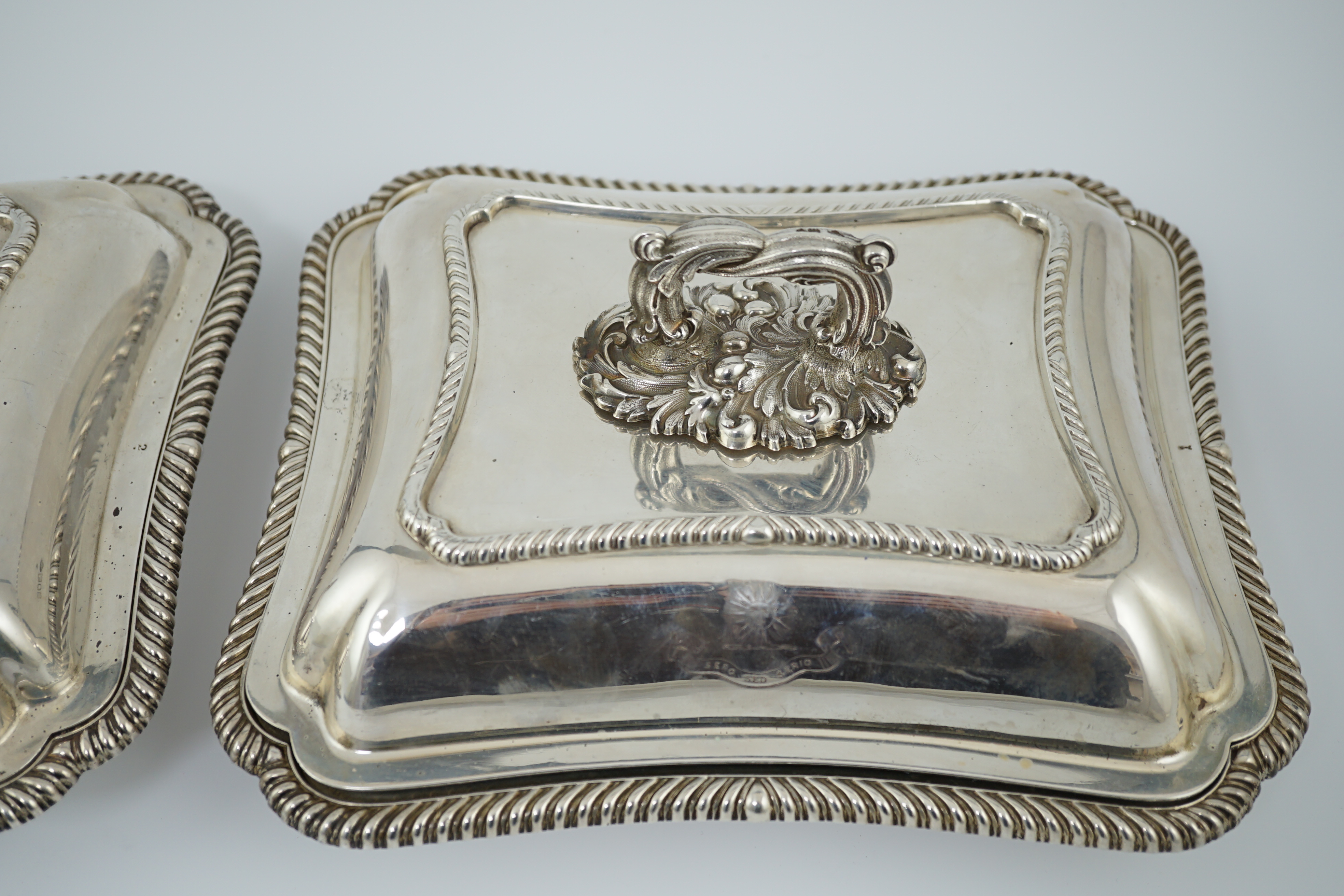 A pair of Edwardian silver shaped rectangular entrée dishes and covers with handles, by Goldsmiths & Silversmiths Co Ltd